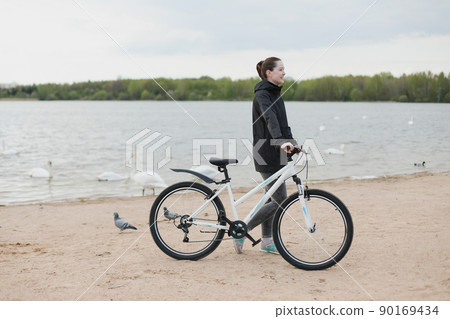 A young woman with a bicycle on the lake 90169434