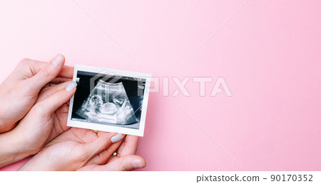 Ultrasound photo pregnancy baby. Woman hands holding ultrasound pregnant picture on pink background. Concept maternity, pregnancy, childbirth. Ultrasound photo pregnancy baby. Woman hands holding ultrasound pregnant picture on pink background. Concept maternity, pregnancy, childbirth. 90170352
