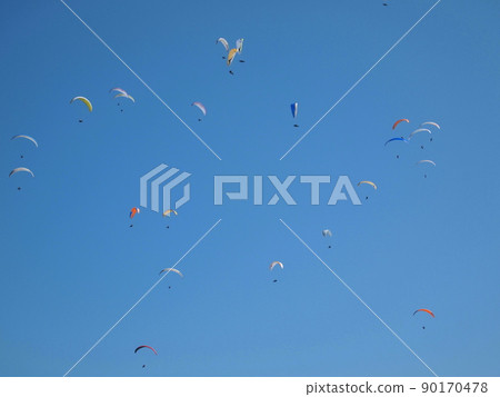 A paraglider floating in the blue sky A paraglider floating in the blue sky 90170478