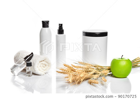 Spa cosmetics, jar of cream, oil with wheat, white cosmetic bottles with apple and wheat towel, candle, soap isolated on white. Without label. Spa cosmetics, jar of cream, oil with wheat, white cosmetic bottles with apple and wheat towel, candle, soap isolated on white. Without label. 90170725