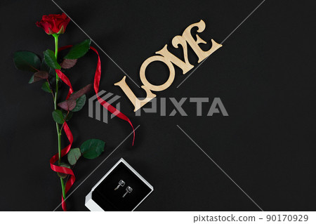 One dark red rose with red ribbon and box with earrings on black One dark red rose with red ribbon and box with earrings on black 90170929