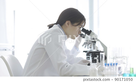 一個穿白大褂的女人透過顯微鏡看 90171050