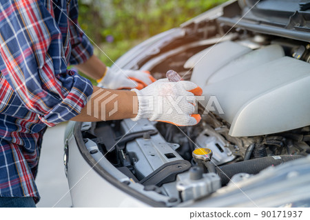 Asian auto mechanic check for repair under the hood of broken down car on the side of the road. 90171937