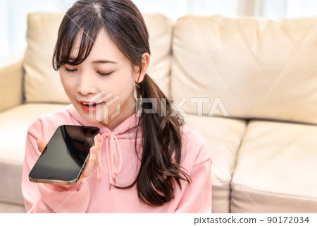 A young woman who operates a smartphone by voice input 90172034