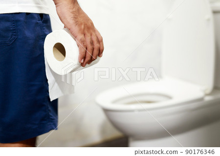 Man suffers from diarrhea hand hold tissue paper roll in front of toilet bowl. constipation in bathroom. Treatment stomach pain and Hygiene, health care 90176346