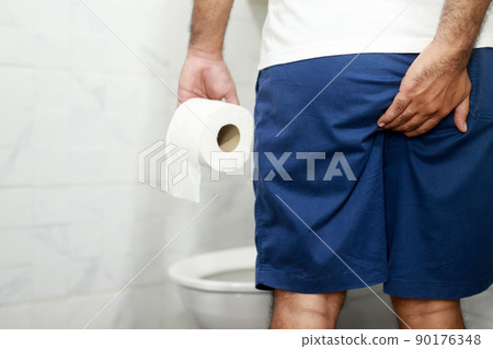 Man suffers from diarrhea hand hold tissue paper roll in front of toilet bowl. constipation in bathroom. Treatment stomach pain and Hygiene, health care 90176348