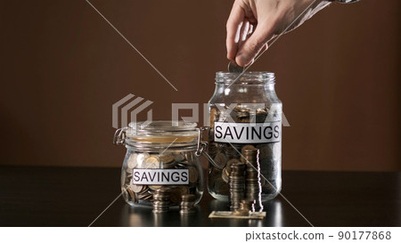 Hand of Man Putting a Coin into a Glass with Savings. Slow Motion. Investment and Personal Finance Management Concept 90177868