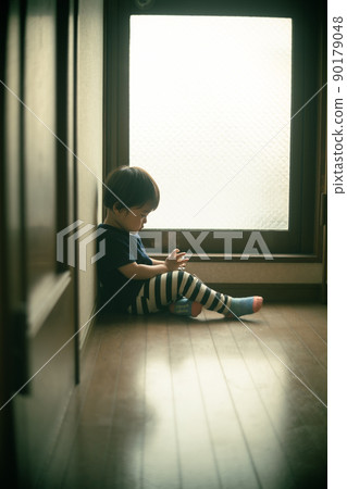 A little lonely 2-year-old boy playing alone at the end of the corridor 90179048