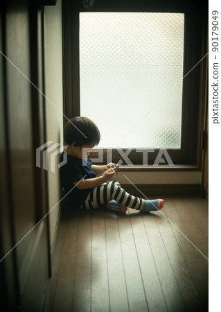 A little lonely 2-year-old boy playing alone at the end of the corridor A little lonely 2-year-old boy playing alone at the end of the corridor 90179049