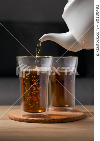Pour hot tea into a glass clear 90180493