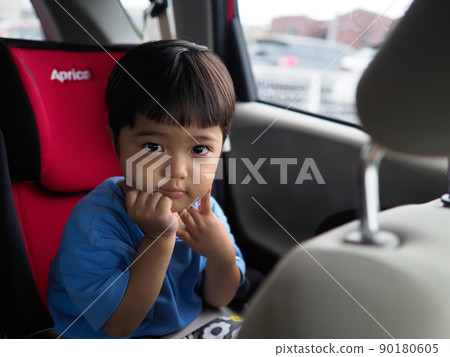 A 3-year-old boy looking at the driver with a serious look from the back seat of the car (the car is parked) A 3-year-old boy looking at the driver with a serious look from the back seat of the car (the car is parked) 90180605