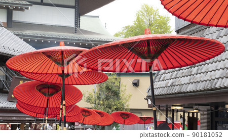 A close-up of walking in a row with a red Japanese umbrella in the old streets of Japan A close-up of walking in a row with a red Japanese umbrella in the old streets of Japan 90181052