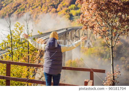 Montenegro. Woman touriste in background of Dzhurdzhevich Bridge Over The River Tara foggy morning. Travel around Montenegro concept. Sights of Montenegro 90181704