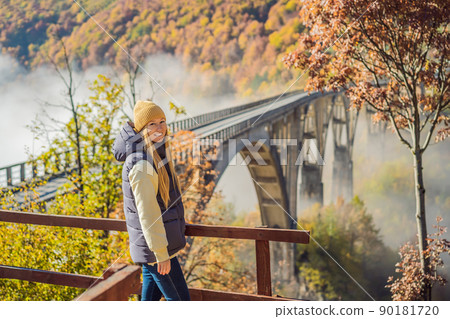 Montenegro. Woman touriste in background of Dzhurdzhevich Bridge Over The River Tara foggy morning. Travel around Montenegro concept. Sights of Montenegro 90181720