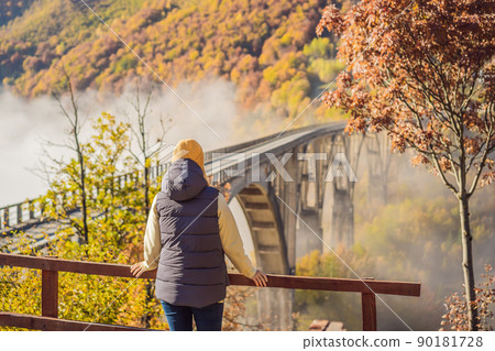 Montenegro. Woman touriste in background of Dzhurdzhevich Bridge Over The River Tara foggy morning. Travel around Montenegro concept. Sights of Montenegro 90181728