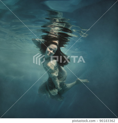 A girl in a shiny dress swims underwater A girl in a shiny dress swims underwater 90183362