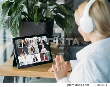 E-learning web chat. Distance education. Professional webinar. Female coach in headphones greeting students on tablet screen in virtual class. E-learning web chat. Distance education. Professional webinar. Female coach in headphones greeting students on tablet screen in virtual class. 90183821