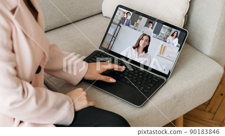 Video conference. Remote business. Telecommuting network. Female employee working online discussing strategy with diverse team on laptop screen on couch at home office. Video conference. Remote business. Telecommuting network. Female employee working online discussing strategy with diverse team on laptop screen on couch at home office. 90183846