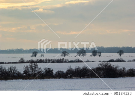Natural sunset sunrise over field or meadow. The color of the sky over the winter snowy ground. Landscape under a picturesque sky at sunset. Dawn of the sun. Natural sunset sunrise over field or meadow. The color of the sky over the winter snowy ground. Landscape under a picturesque sky at sunset. Dawn of the sun. 90184123