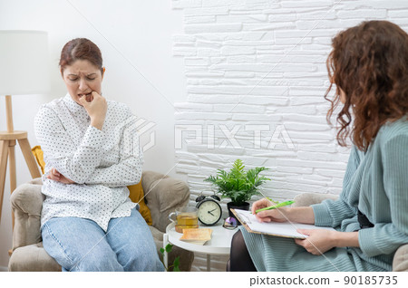 Worried caucasian woman at a session with a psychotherapist. Worried caucasian woman at a session with a psychotherapist. 90185735