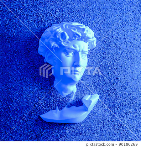 Bust head of David plaster antique in the sand on the beach. 90186269