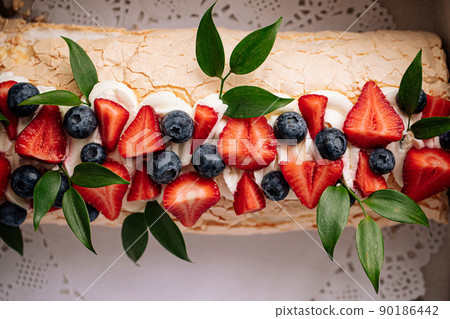 Meringue roll dessert with berries 90186442