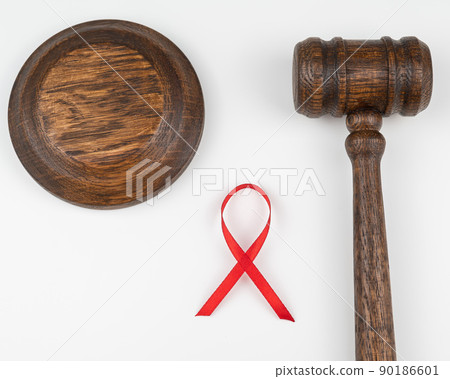 Judicial gavel and red ribbon on a white background. Symbol of the fight against AIDS. 90186601