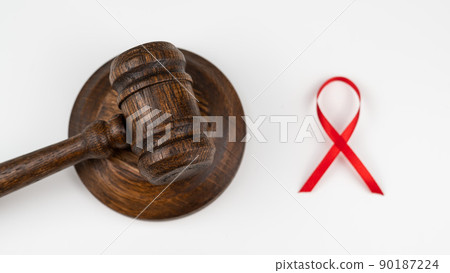 Judicial gavel and red ribbon on a white background. Symbol of the fight against AIDS. 90187224