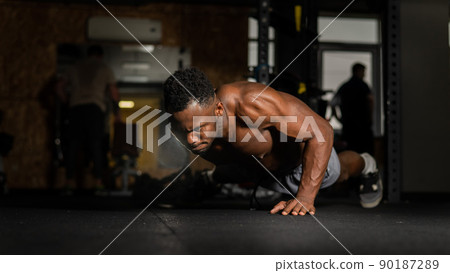 African american man doing one arm push ups in the gym. African american man doing one arm push ups in the gym. 90187289