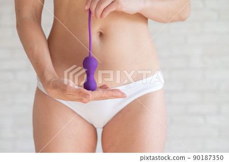 Faceless woman in white panties and with a bare tummy holds a kegel trainer. Latex vaginal vibrator for training the pelvic floor muscles with an antenna. The device for imbuilding. Women Health. Faceless woman in white panties and with a bare tummy holds a kegel trainer. Latex vaginal vibrator for training the pelvic floor muscles with an antenna. The device for imbuilding. Women Health. 90187350
