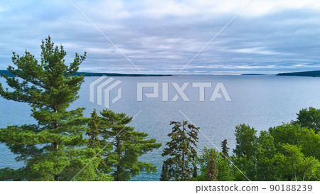 View next to green trees of large lake and storm clouds 90188239