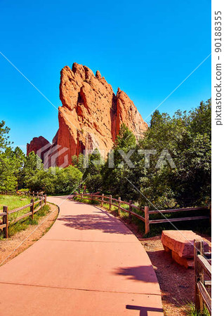 Paved park path with stone bench and background of large red pillar of rock Paved park path with stone bench and background of large red pillar of rock 90188355