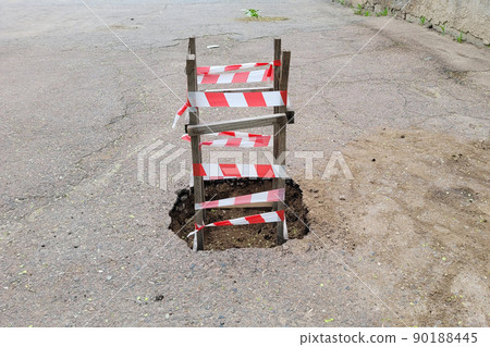 Wooden fence with red warning tape around the dug hole Wooden fence with red warning tape around the dug hole 90188445