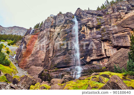 Large waterfall over vertical cliffs in mountains 90188640