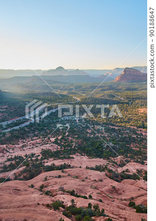 Nature shot of sloping rock leading into forest and road towards the horizon 90188647