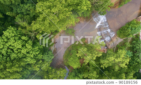 Aerial looking down at cascading waterfalls in river surrounded by green forest Aerial looking down at cascading waterfalls in river surrounded by green forest 90189156