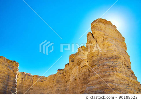 Sun blocked by white and brown stone pillars with blue sky Sun blocked by white and brown stone pillars with blue sky 90189522