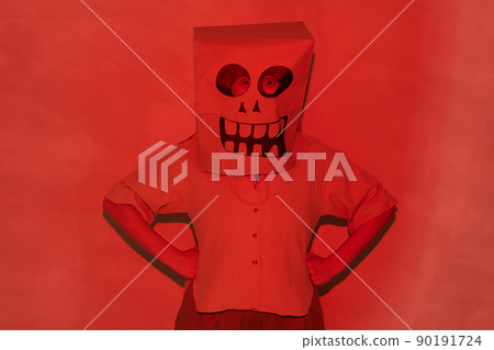 Portrait of unrecognizable person in Halloween mask made of paper bag standing with hands on hips in red light Portrait of unrecognizable person in Halloween mask made of paper bag standing with hands on hips in red light 90191724