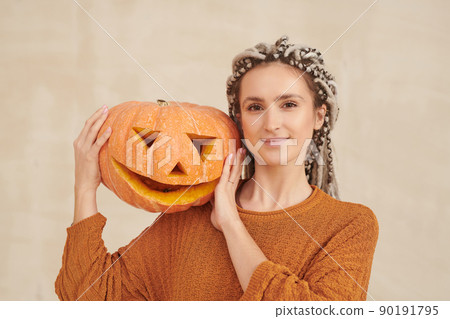 Portrait of smiling hipster young woman with white dreads posing with jack-o-lantern on shoulder against isolated background, Halloween concept Portrait of smiling hipster young woman with white dreads posing with jack-o-lantern on shoulder against isolated background, Halloween concept 90191795