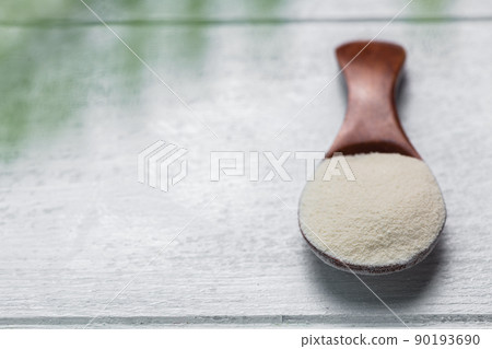 Collagen powder in spoon on wooden white background. 90193690