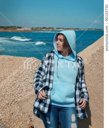 Teenager girl in light blue hoodie and plaid shirt near the sea, Clothing mockup Teenager girl in light blue hoodie and plaid shirt near the sea, Clothing mockup 90193792