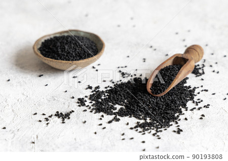 Scoop of Indian spice Black cumin (nigella sativa or kalonji) seeds on white table close up Scoop of Indian spice Black cumin (nigella sativa or kalonji) seeds on white table close up 90193808