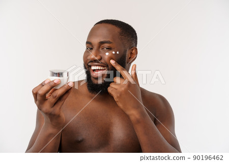 African handsome man applying cream on his face. Man's skin care concept African handsome man applying cream on his face. Man's skin care concept 90196462