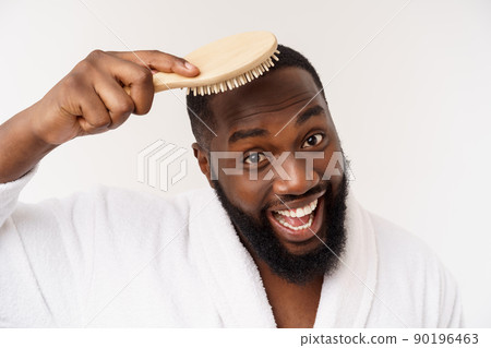Portrait of handsome young african american man combing his hair in bathroom. Isolated over white background Portrait of handsome young african american man combing his hair in bathroom. Isolated over white background 90196463