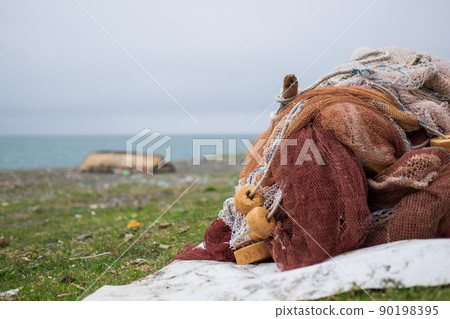 Pile of old fishing nets dry on shore. 90198395