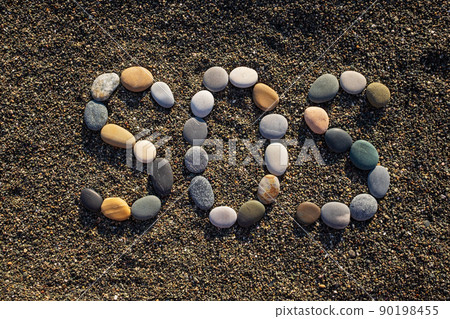 SOS message made with stones on the beach 90198455