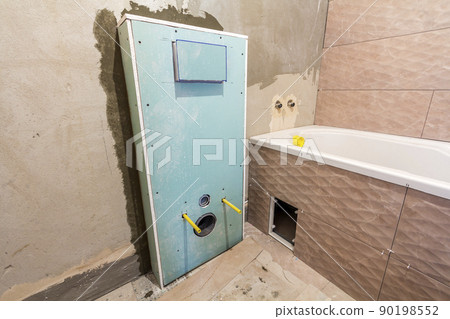 Unfinished reconstruction of bathroom or toilet with ceramic tiles installed on walls of drywall, place for lavatory and bath. 90198552