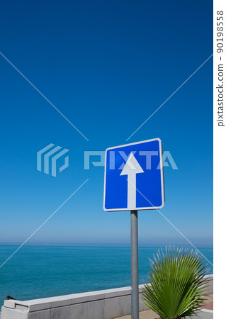 Square road sign with white arrow on blue sky background. Square road sign with white arrow on blue sky background. 90198558