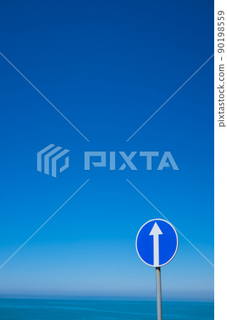 Circle road sign with white arrow on blue sky background. Circle road sign with white arrow on blue sky background. 90198559