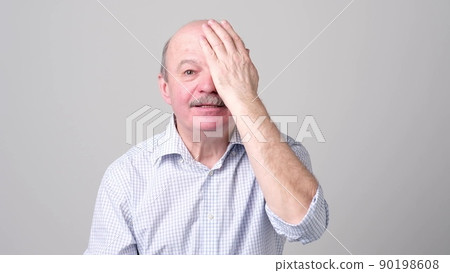 man covering one eye during vision examination trying to see letters. man covering one eye during vision examination trying to see letters. 90198608